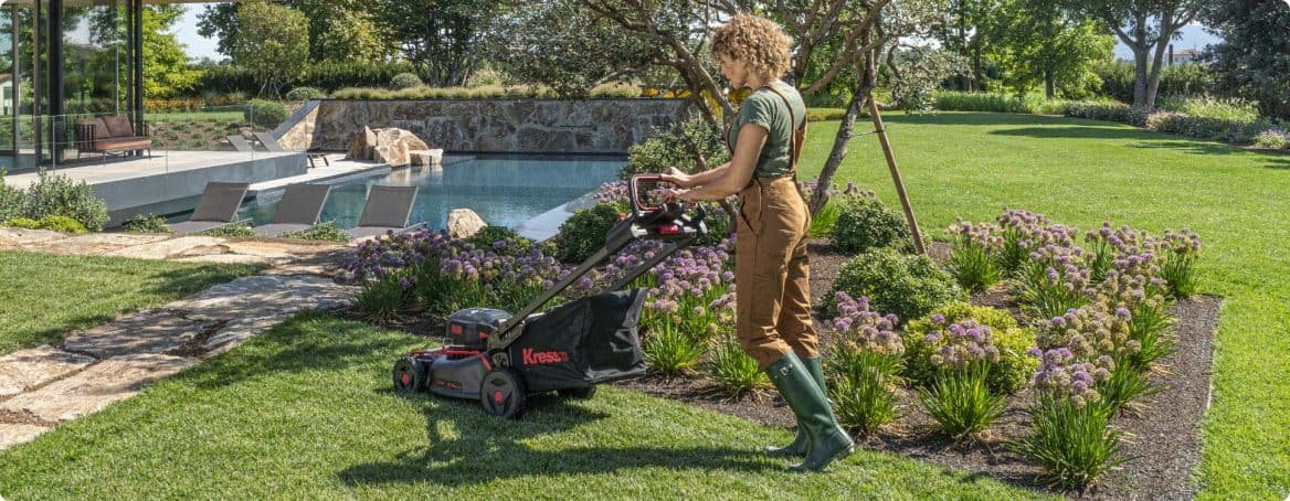 Personne qui tond son gazon dans un beau jardin avec piscine